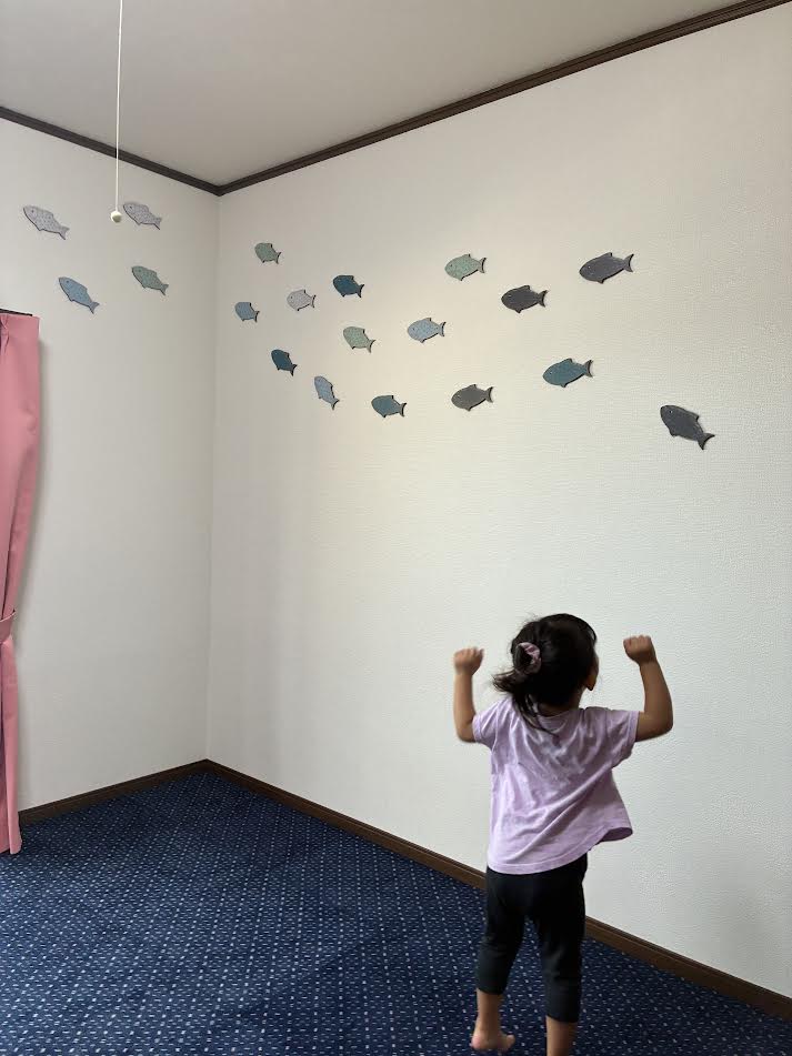 壁に貼った魚のステッカーに大喜びする孫娘